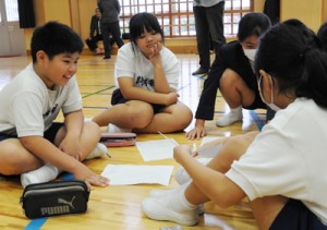 描いた絵を見せ合い、感じた事などを話し合う児童ら＝２０日、阿木名小中学校体育館