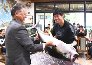 冬季合宿中の実業団チームにキハダマグロを贈った奄美群島地区漁業士会の田畑会長（左）＝１７日、天城町与名間