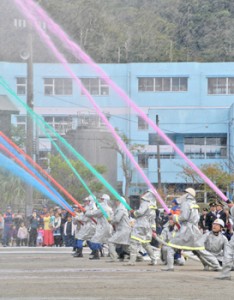 鮮やかに色付けされた水を放つ消防団員ら＝６日、奄美市名瀬の伊津部小学校校庭