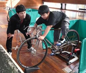 競技用自転車に乗る参加者と指導する新納選手＝１３日、奄美市名瀬