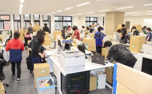 段ボール箱を積み上げた新庁舎内で引っ越し作業に汗を流す市職員ら＝９日、奄美市名瀬