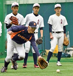 捕球の基本を教えるＥＮＥＯＳの田中将也内野手（手前）＝９日、名瀬運動公園屋内練習場