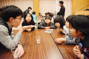 講師の学生と科学実験の結果を見詰める児童＝１７日、宇検村の元気の出る館