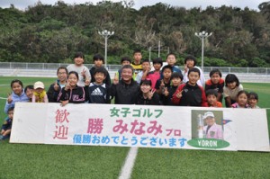 教室に参加した子どもたちと笑顔で記念撮影する勝選手と父の秀樹さん（前列中央）＝２４日、与論町多目的運動広場