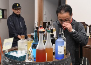 黒糖焼酎を試飲する鎌田さん（右）＝１日、龍郷町の町田酒造