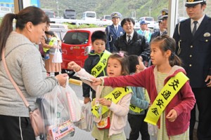 買い物客に交通安全を呼び掛け、チラシを手渡す奄美署員の子どもたち＝９日、奄美市名瀬