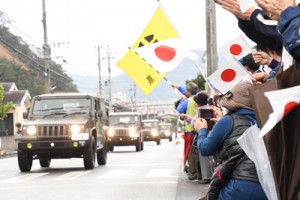 奄美大島に到着し、市民に迎えられながら奄美市内を通過する自衛隊車両＝１５日、奄美市名瀬大熊町