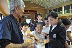 リュウキュウアユに触れて雄と雌の違いを学ぶ児童たち＝２８日、龍郷町の戸口小学校