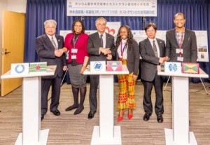 調印を終え、握手を交わす(左から)伊地知和泊町長とドミニカ国外務省職員、山与論町長とアンティグア・バーブーダ財務・コーポレートガバナンス省職員、赤地知名副町長とグレナダ外務省職員=4日 内閣府・内閣官房オリパラ事務局会見室