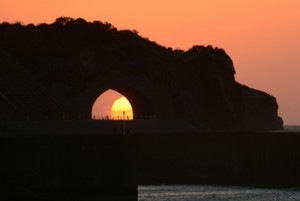  かがんばなトンネル越しに沈んでいく夕日＝１３日午後６時２３分、龍郷町円