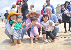 赤ちゃんの足を海水に浸して健やかな成長を願うイベント参加者＝７日、知名町屋子母