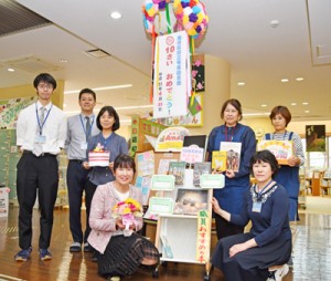 開館１０周年を手づくりのくす玉で祝う奄美図書館の職員ら＝２３日、奄美市名瀬