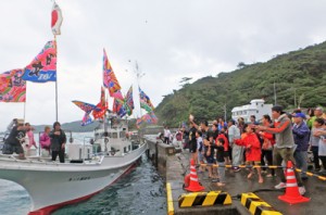 漁船から振る舞われる祝い餅に手を伸ばす参加者ら＝ ２８日、瀬戸内町加計呂麻島芝