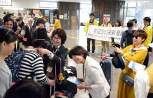 横断幕と黒糖レイでツアー一行を出迎えた歓迎セレモニー＝９日、奄美空港