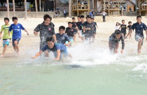 駆け足で海に入る小中学生ら＝７日、奄美市笠利町の用安海岸