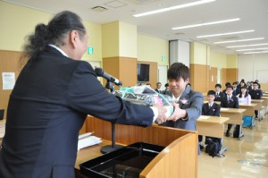 福山校長からノートパソコンを貸与される新入生＝１２日、奄美市名瀬