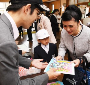 新１年生と保護者に防犯啓発グッズなどを手渡す奄美署員（左）＝８日、小宿小学校  