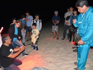 ウミガメ観察時の注意点を説明する興会長（左）＝６日、奄美市名瀬の大浜海岸