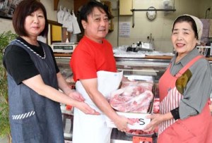  豚肉を贈呈する㈲宮本商店の宮本代表（中央）とＮＰＯの西野代表＝徳之島町亀津 