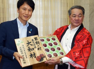 特産のスモモを三反園知事に手渡す伊集院村長（右）＝７日、鹿児島市の県庁