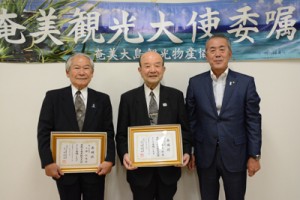 奄美観光大使に任命された英さん（中央）と小勝さん（左）＝１９日、奄美市名瀬