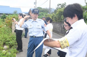 消防職員の案内で火災現場周辺を視察する研究チーム＝１０日、奄美市笠利町笠利