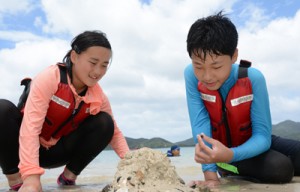 ヤドカリを興味深そうに見つめる児童ら＝７日、宇検村タエン浜