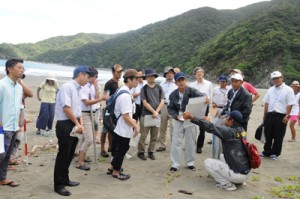 嘉徳海岸を視察する鹿児島地裁の裁判官と被告、原告両関係者＝３０日、瀬戸内町