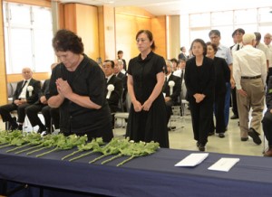 手を合わせて犠牲者の冥福を祈る参列者＝１５日、奄美市名瀬