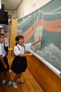 黒板アートの前で記念に撮影してもらう児童＝１日、龍郷町の秋名小学校