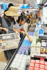 品薄が続いていた牛乳などの商品を手に取る買い物客＝１７日、和泊町のＡコープ和泊店