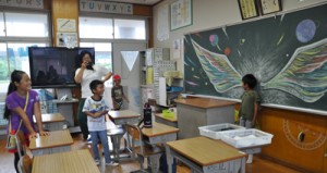 黒板アートの前で記念に撮影してもらう児童＝１日、龍郷町の秋名小学校