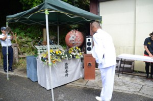 臨時に設置された祭壇に向かい、祈りをささげる海自第１航空群司令の川村伸一海将補＝１５日、奄美市名瀬