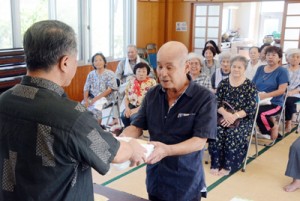 伊集院村長（左）から敬老年金が贈られた支給式＝１３日、大和村大棚公民館