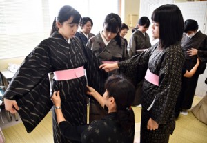 紬協組青年部の指導で着付けに挑戦する生徒たち。着用体験のある生徒は大島紬への関心が高かった＝２０１８年１２月４日、古仁屋高校