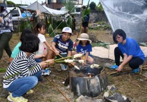 岳に巻き付けたパン生地を焼き上げる子どもたち＝２９日、徳之島町手々