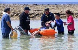 徳之島初のビーチ用車いすに乗り、海水浴を楽しむ障がい者と保護者ら＝１４日、伊仙町伊仙  