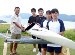 寄贈されたカヌーのそばで笑顔を見せる大島北高カヌー部メンバーと白畑さん（左）＝７日、赤木名海岸