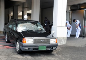 摘出された臓器を乗せ、奄美空港に向かうタクシーと、見送る病院スタッフ＝２２日、奄美市名瀬の県立大島病院