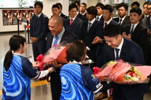 花束を受け取る（左から）アレックス・ラミレス監督、佐野恵太選手＝３１日、奄美市笠利町の奄美空港