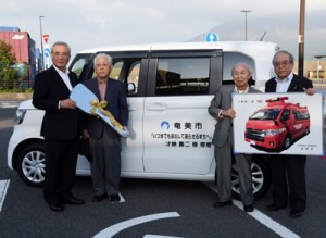 奄美市へ車両を寄贈した才納さん（左から２人目）＝４日、鹿児島市