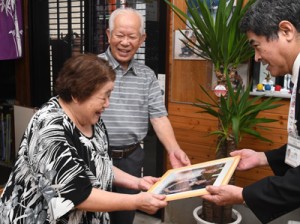 金婚式の記念写真を受け取る福山政雄さん（中央）と幸子さん（左）＝１５日、奄美市住用町