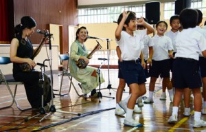 元ちとせさん（左から２人目）らと一緒に島唄を歌い踊る児童＝２９日、瀬戸内町