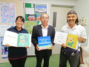 教育委員会を訪れ、町岡教育長（中央）に絵本の制作を報告した原田さん（右）と山田さん＝１０月３０日、与論町
