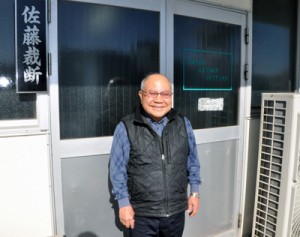 笑顔で会社の前に立つ佐藤徹義さん＝２０１９年１１月、神戸市長田区