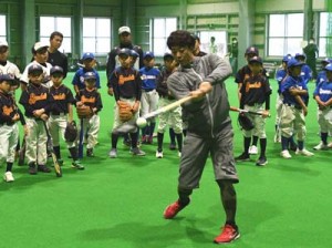 野球教室で打撃フォームを披露する鶴岡選手（中央）＝１２日、徳之島町徳和瀬