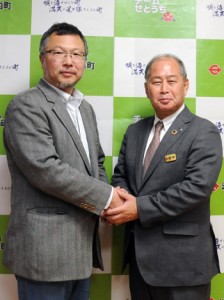 記者会見で、鎌田愛人瀬戸内町長（右）と握手する㈱ＴＡＲＧＥＴの立石聡明社長＝２８日、同町役場