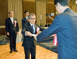 黒糖焼酎の入賞者を代表して表彰状を受け取る西平本家の小畠康幸代表取締役＝１４日、鹿児島市のホテル