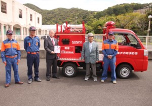 日本損保協から与路集落に贈られた消防ポンプ車と保島区長（右から２番目）、鎌田瀬戸内町長（同３番目）ら＝１７日、瀬戸内消防分署（提供写真）