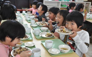 牛肉をおいしそうに頬張る園児ら＝３日、和泊町